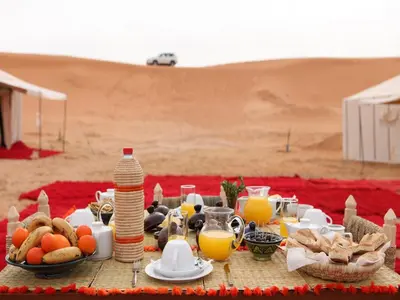 a table with food and drinks in the desert at Merzouga Boho Camp in Merzouga