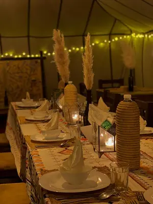 a table with plates and dishes on it with lights at Merzouga Boho Camp in Merzouga