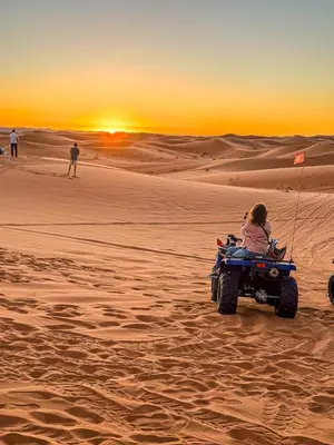 a woman sitting on a wheeler in the desert at Merzouga Sahara Nights Tents in Merzouga