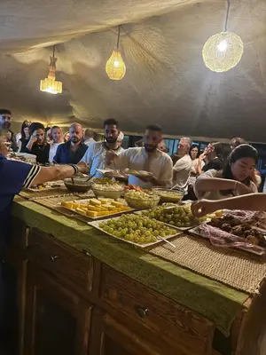 a group of people standing around a buffet of food at Merzouga Sahara Nights Tents in Merzouga