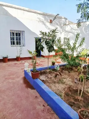 a house with trees and a blue curb at Authentic Berber Home Retreat Ourika Valley in Aghmat