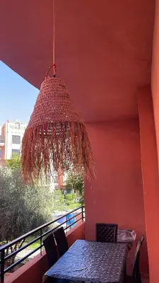 a table and chairs on a balcony with a chandelier at Premium village marrakech in Ville Nouvelle