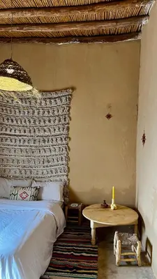 a bedroom with a bed and a table with a candle at Merzouga Nomad House in Merzouga