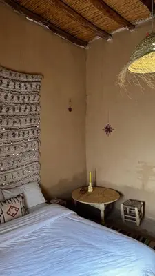 a bedroom with a bed and a table with a candle at Merzouga Nomad House in Merzouga