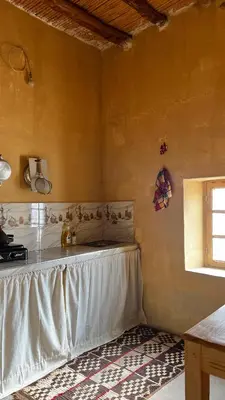 a corner of a room with a table and a window at Merzouga Nomad House in Merzouga