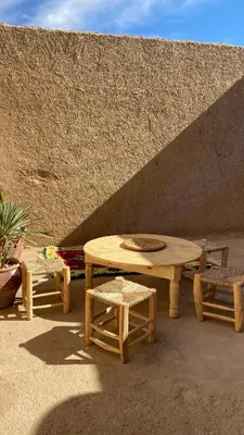 a picnic table and two chairs and a table and benches at Merzouga Nomad House in Merzouga