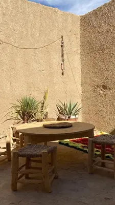 a wooden picnic table with two chairs and plants at Merzouga Nomad House in Merzouga