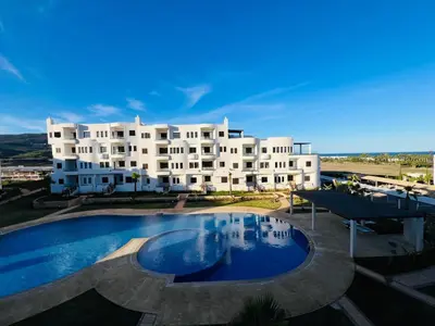 a large white building with a large swimming pool at Colina Smir par Immo Marina Vacances de Rêve C1-10 in Oulad Akkou
