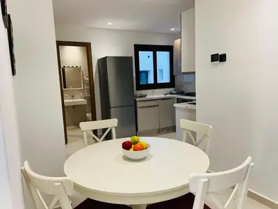 a white table in a kitchen with a bowl of fruit on it at Colina Smir par Immo Marina Vacances de Rêve C1-10 in Oulad Akkou