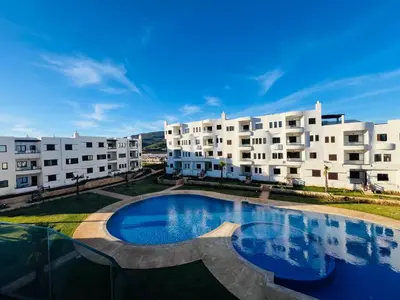 a swimming pool in front of some apartment buildings at Colina Smir par Immo Marina Vacances de Rêve C1-10 in Oulad Akkou