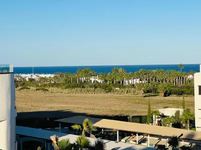 a building with a view of a field and the ocean at Colina Smir par Immo Marina Vacances de Rêve C1-10 in Oulad Akkou