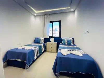 two beds in a room with blue and white sheets at Colina Smir par Immo Marina Vacances de Rêve C1-10 in Oulad Akkou