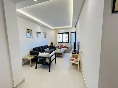 a living room with a black couch and chairs at Colina Smir par Immo Marina Vacances de Rêve C1-10 in Oulad Akkou