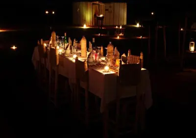 a long table with chairs and lights at night at Sahara Relax Camps in Zagora