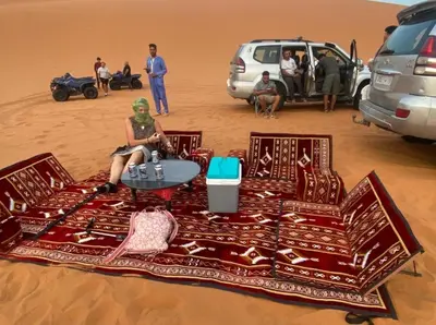 a woman sitting on a blanket in the desert at Sahara desierto Camp in Merzouga