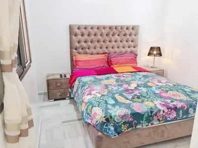 a bedroom with a large bed with a floral bedspread at Confort in Fès