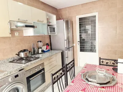 a kitchen with a washing machine and a table with a table cloth at Confort in Fès