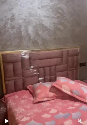 a bed with a wooden head board with pink sheets at فاس in Fès