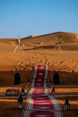 a carpeted road in the desert with two windmills at Merzouga Desert Dreams in Merzouga