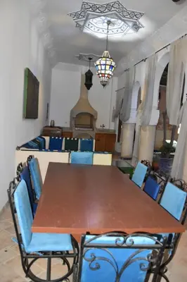 a dining room with a wooden table and blue chairs at Chambre topaze - Riad lotus bleu in Fès