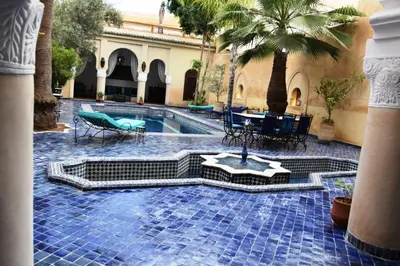 a courtyard with a pool with tables and chairs at Chambre topaze - Riad lotus bleu in Fès