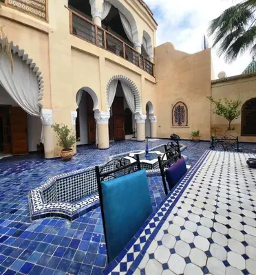 a courtyard of a building with chairs and tables at Chambre topaze - Riad lotus bleu in Fès