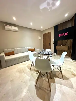 a living room with a couch and a table and chairs at Garden View- Gueliz-Majorelle appartement 2 chambres- Wifi et piscines in Oulad Akkou