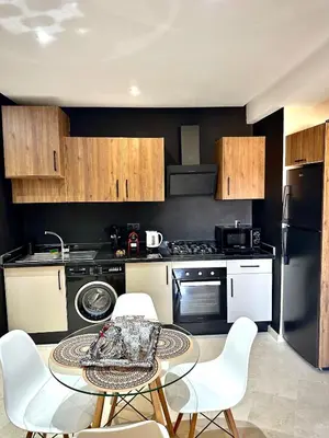 a kitchen with a table and white chairs in it at Garden View- Gueliz-Majorelle appartement 2 chambres- Wifi et piscines in Oulad Akkou