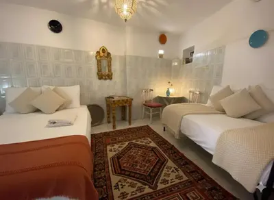 a room with two beds and a table and a table at Fes Medina Vibes Hostel in Fès