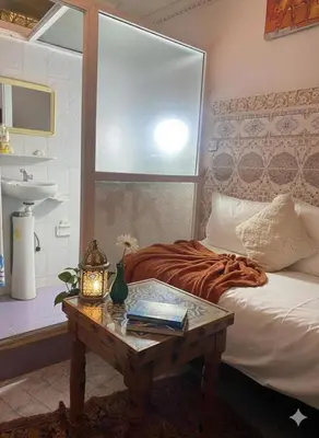 a bedroom with a bed with a table and a window at Fes Medina Vibes Hostel in Fès