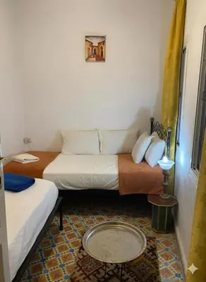 a small room with two beds and a table at Fes Medina Vibes Hostel in Fès