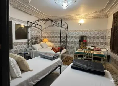 a room with two beds and a table and chairs at Fes Medina Vibes Hostel in Fès