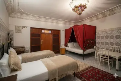 a bedroom with two beds and a table and a couch at Fes Medina Vibes Hostel in Fès
