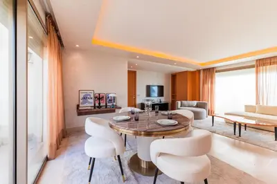 a living room with a wooden table and white chairs at Riva Molière Parking Elegance in Oulad Akkou