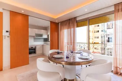 a dining room with a table and white chairs at Riva Molière Parking Elegance in Oulad Akkou