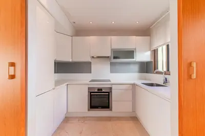 a kitchen with white cabinets and a sink at Riva Molière Parking Elegance in Oulad Akkou