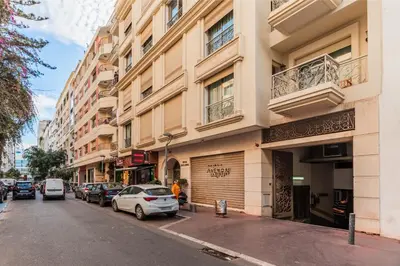 a street with cars parked in front of buildings at Riva Molière Parking Elegance in Oulad Akkou