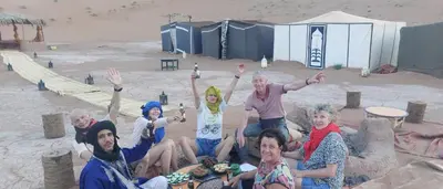a group of people posing for a picture in the sand at Dar Chez Ali in Mhamid