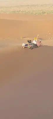 two people laying on the sand on a beach at Dar Chez Ali in Mhamid
