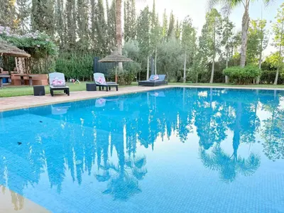 a pool with blue water and two chairs and trees at Villa Five Collection - Private Luxury & Heated Pool