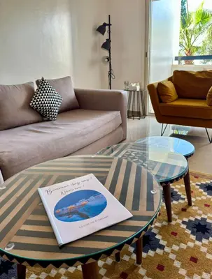 a living room with a coffee table with a book on it at Le cocon d'Asilah Mer et Confort in Oulad Akkou