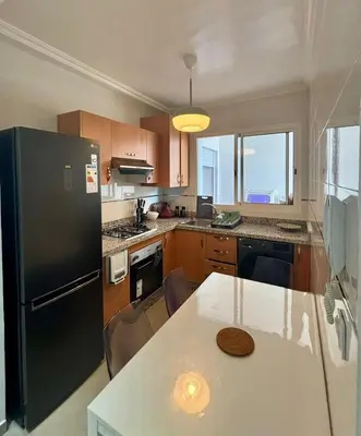 a kitchen with a black refrigerator and a table at Le cocon d'Asilah Mer et Confort in Oulad Akkou