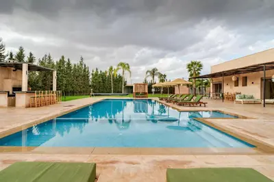a large swimming pool with blue water in a yard at Villa privée sans vis-à-vis,Padel,Tennis, Five in Oulad Mazoug