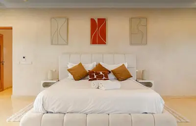 a bedroom with a white bed with three paintings on the wall at Villa privée sans vis-à-vis,Padel,Tennis, Five in Oulad Mazoug