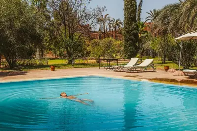 a woman laying in the water in a swimming pool at Villa Riad Soles Heated pool Luxury and Beauty in Douar Soukkane