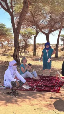 a group of people sitting on a blanket on the ground at Bivouac Desert Du Maroc in Mhamid