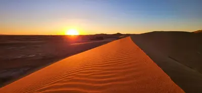 a sunset in the desert with a sand dune at Bivouac Desert Du Maroc in Mhamid