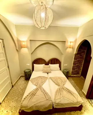 a bedroom with a large bed and a chandelier at Riad Oum h&N in Srarhna