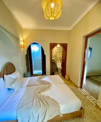 a bedroom with a large white bed with a chandelier at Riad Oum h&N in Srarhna
