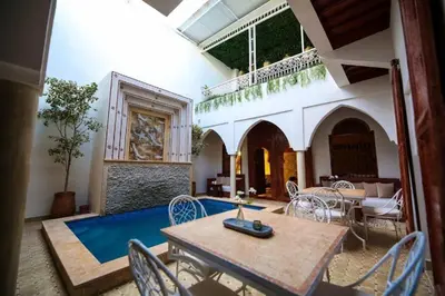 a living room with a table and chairs and a pool at Riad Oum h&N in Srarhna